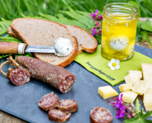 regionales Picknick mit Brot, Ahler Wurst, Käse und Frischkäse auf einer Schieferplatte serviert.